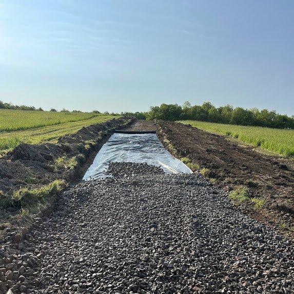 Geotextile fabric and crushed stone road base under construction for a cell tower access road